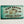 Load image into Gallery viewer, Teal wooden dugout with distressed black lettering on one side
