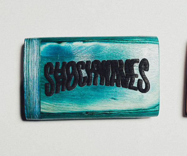 Teal wooden dugout with large distressed black “SHOEMAKERS” lettering